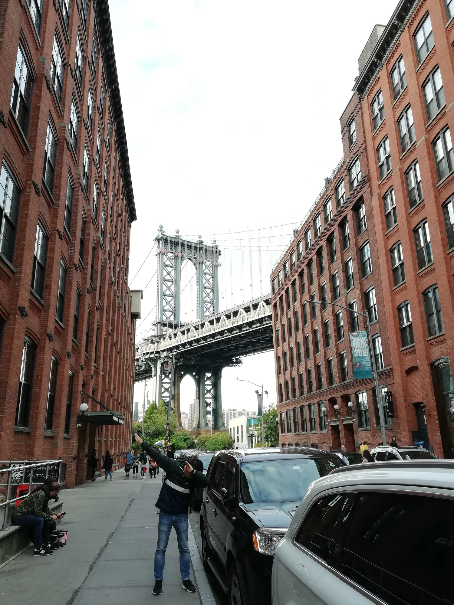 Marco Xu macht vor dem Hintergrund der Brooklyn Bridge auf den Straßen Brooklyns einen Dab.