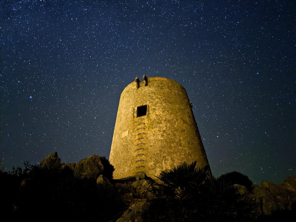 a stone tower at night with a starry sky in the background