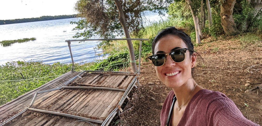 Ein Selfie von Gabriella Araujo an einem Fluss stehend mit einem Holzsteg