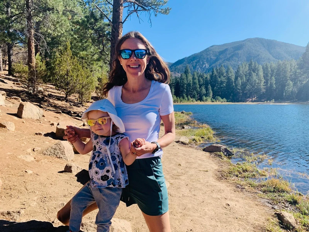 Lydia Kluge with her daughter standing near a lake with mountains and trees