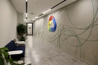 parede no novo escritório com formas feitas por cabos de dados, inclui um logo de Google Cloud (uma nuvem colorida), e um corredor
