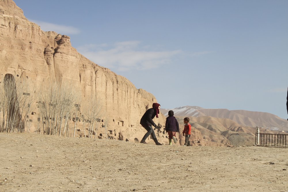 A picture of a woman playing with local children in the Bamiyan Valley of Afghanistan.