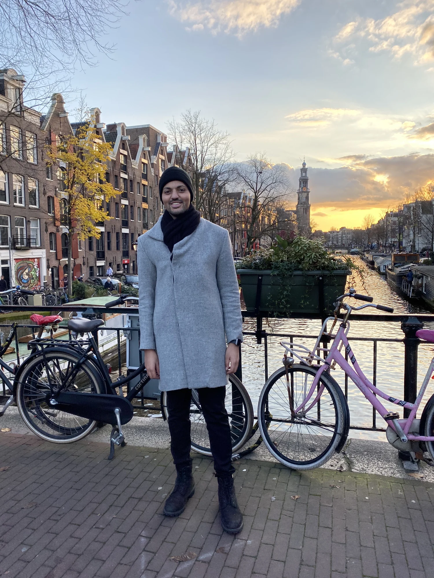 Bilal steht auf einer Grachtenbrücke in Amsterdam. Im Hintergrund der Sonnenuntergang.