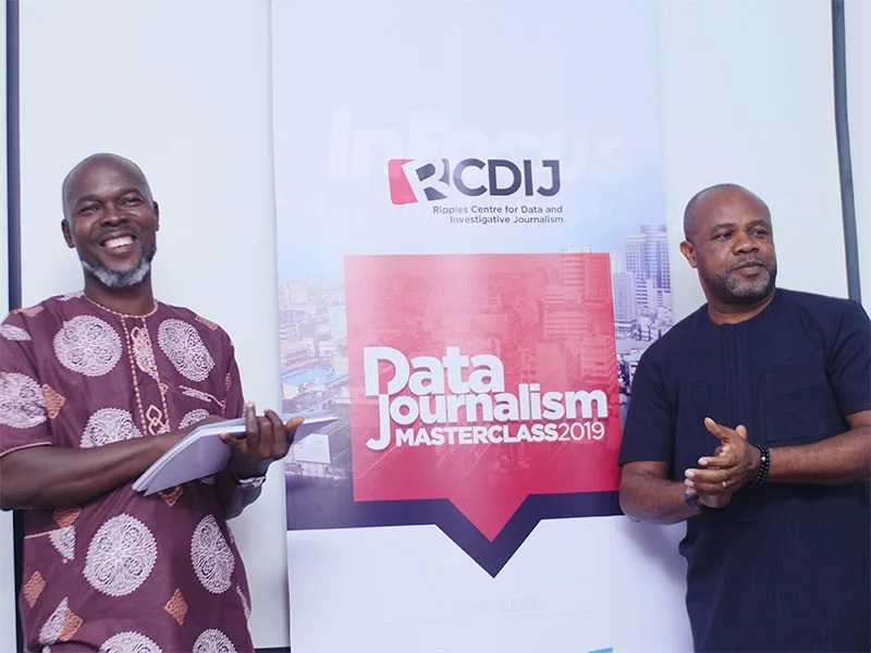 A picture of Edirin Etaghene, Editor, Ripples Nigeria (right) and Samuel Ibemere, Editor-in-Chief, Ripples Nigeria & Executive Director, RCDIJ standing either side of a sign that reads Data Journalism Masterclass 2019.