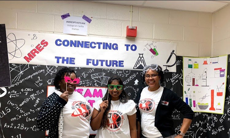 Image of three women in front of a sign that says, "Connecting to the future".