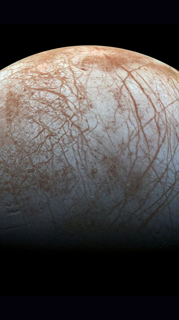 Image of Europa, one of Jupiter’s moons. A white surface with red coloured  scratches.