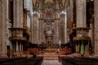 A view of the central nave and main altar. At the back, a majestic stained-glass decoration.