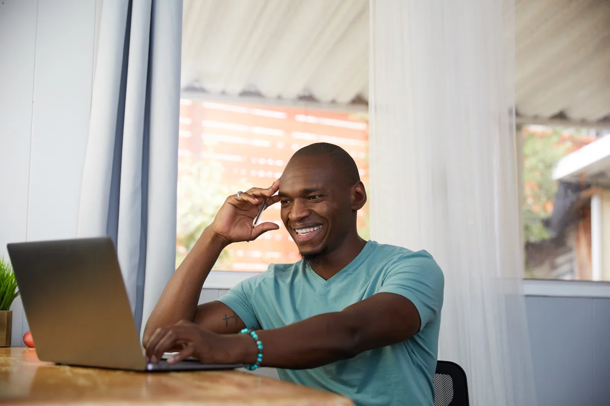 A picture of a man at his desk smiling at his laptop