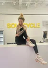 SoulCycle instructor Jenny, based in New York City, poses at the front desk of a SoulCycle studio.