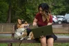 Julia sits on a metal bench with her dog, Keto. She is holding her laptop open and gesturing to the screen.