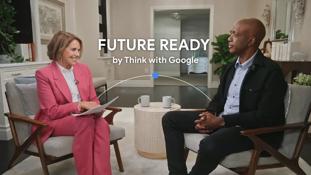 Two people, Katie Couric and James Manyika, sit opposite one another in casual armchairs. A text overlay reading “Future Ready by Think with Google” is centered between them.