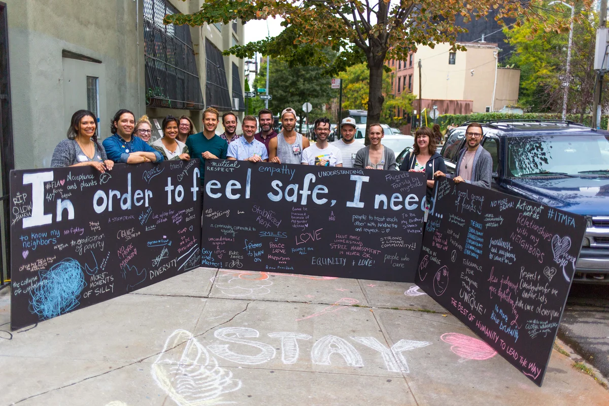 A group smiling around a large poster board that reads “In order to feel safe, I need …”