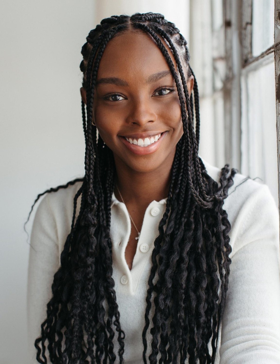 Headshot of Kyla Bolden in a cream button-up sweater, smiling at the camera with her long hair half-up.
