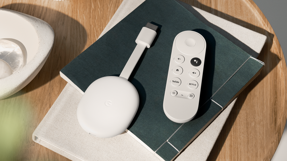 Chromecast with Google TV (HD) and remote lays on top of two books on a coffee table with a decorative bowl nearby.