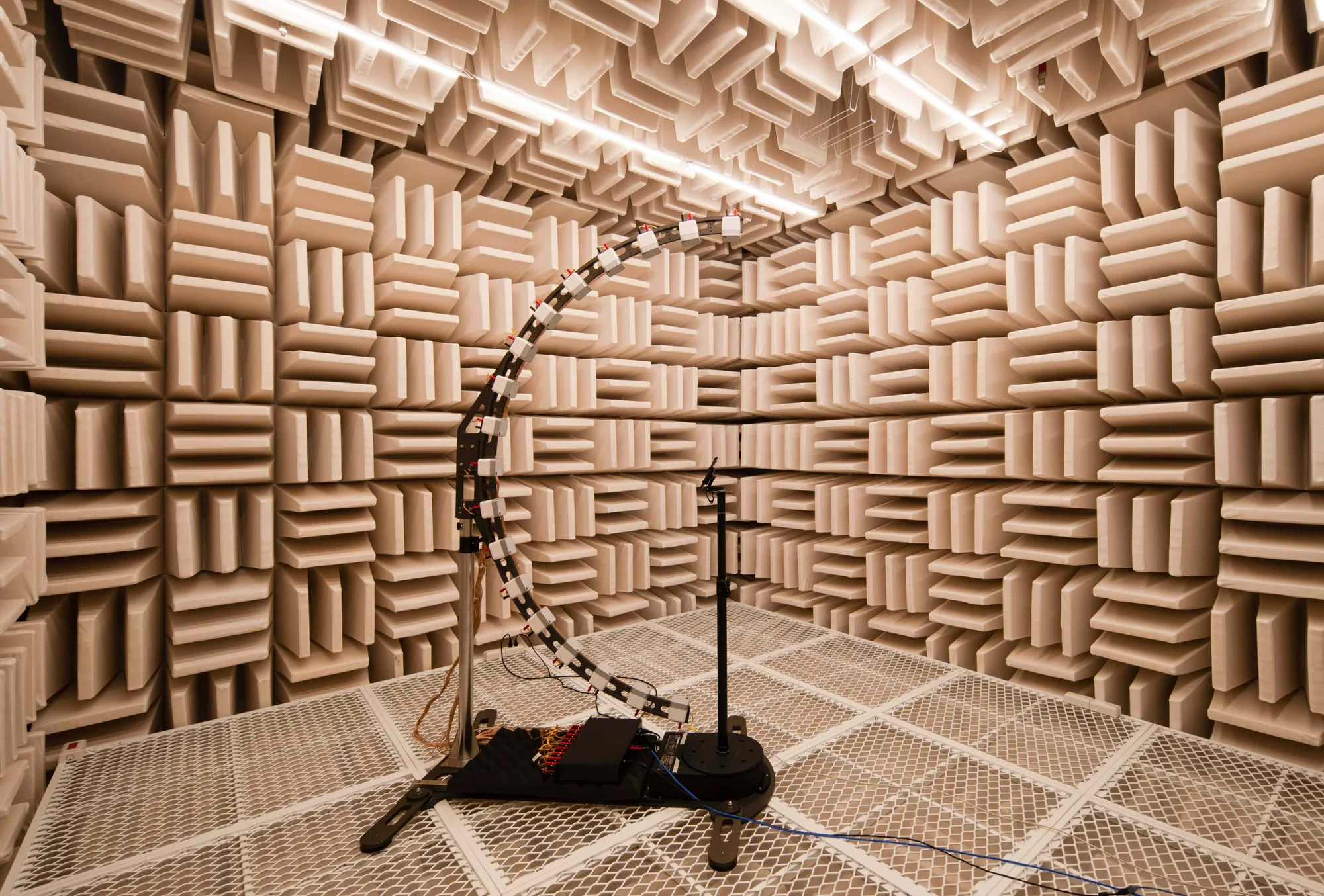 A room with beige floors and walls, with blocks protruding from the walls and ceiling. A large metal device with wires in the middle of the room.