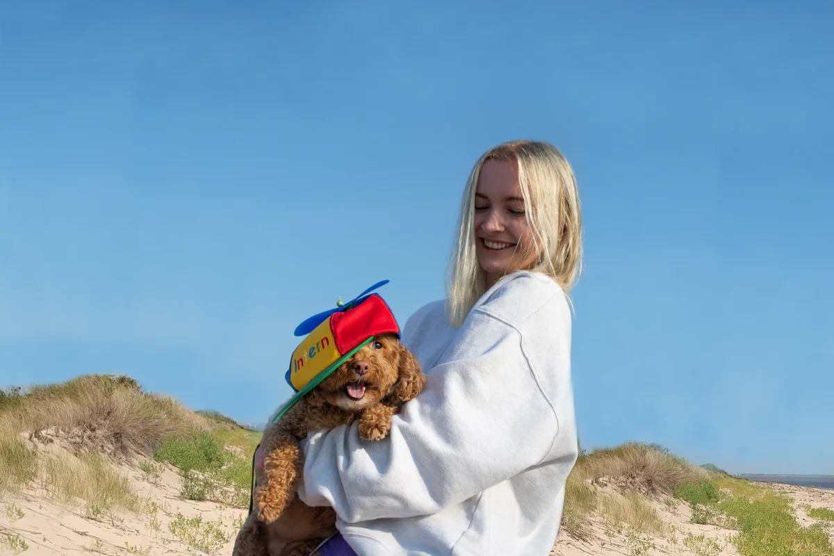 Livia Seibert holding her dog that’s wearing a Google intern hat.