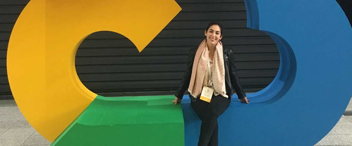 Dina sitting inside a sculpture of a large Google Cloud logo.