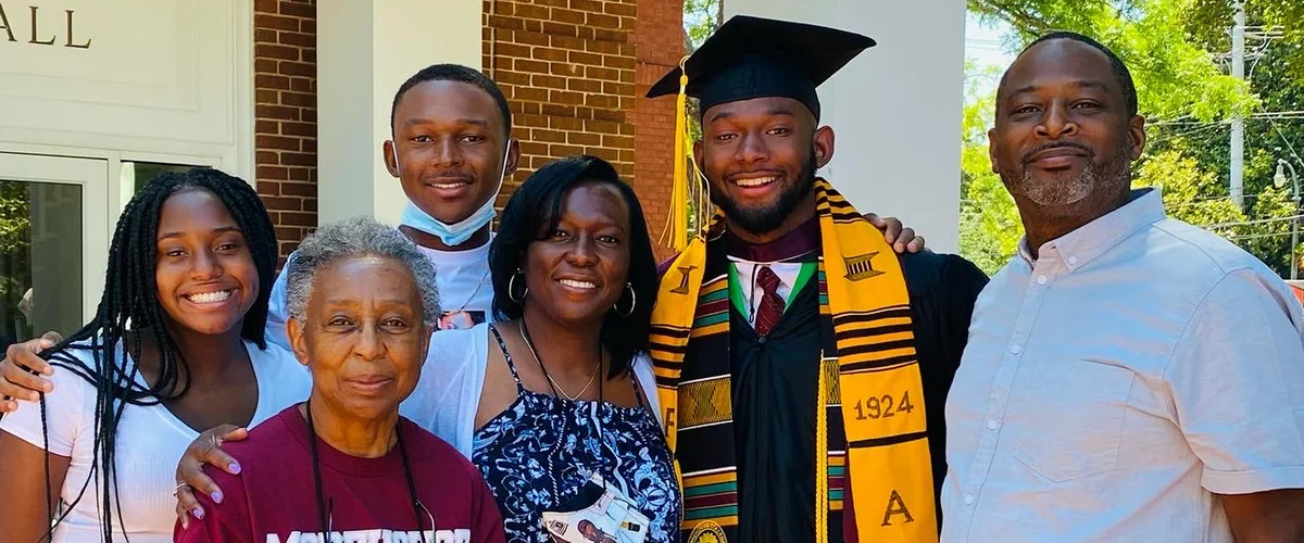 Grant — in his cap, gown and fraternity stole — smiles with family members at his graduation from Morehouse College