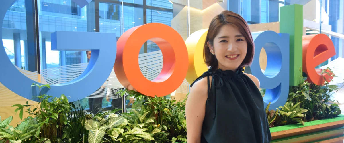 Ikumi standing in front of a large Google sign indoors.