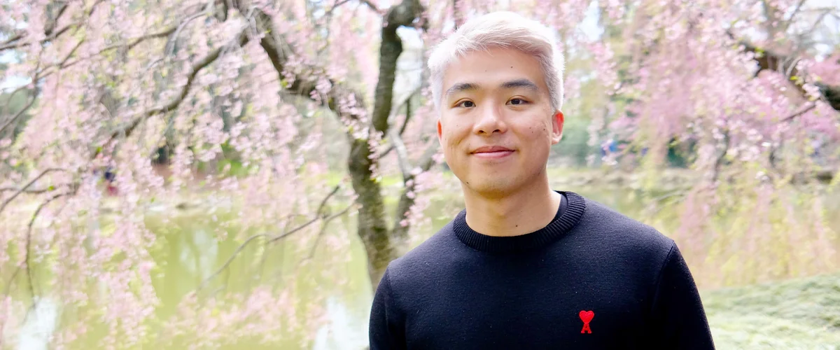 Ken smiling in front of a cherry blossom tree.