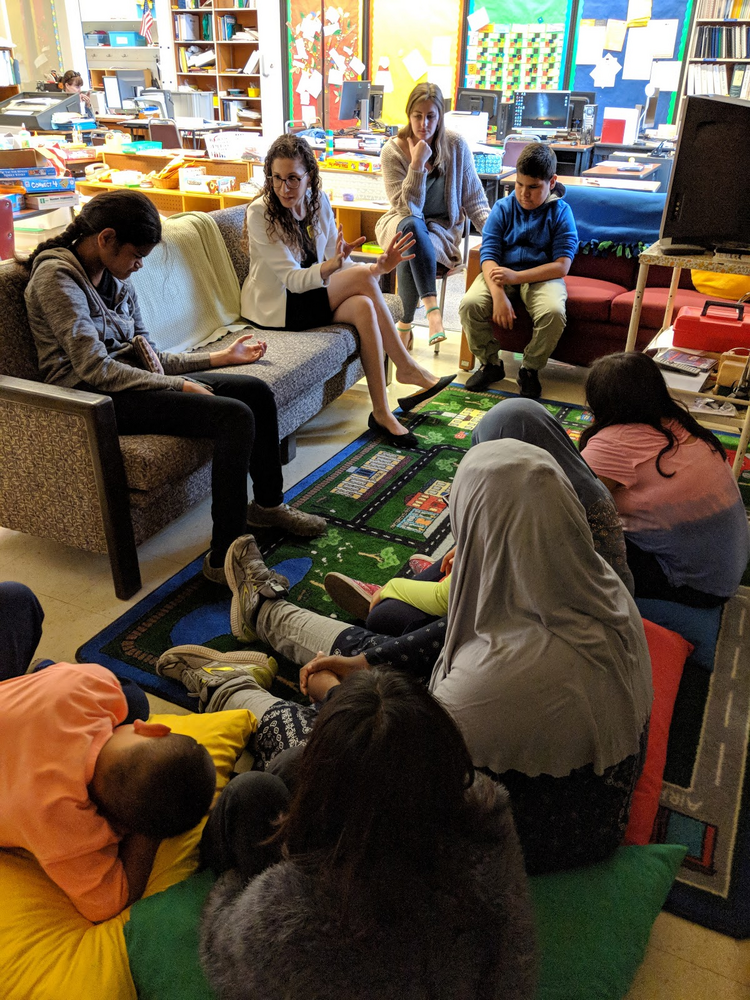 Photo of Laura talking with young students in a classroom at the California School for the Blind