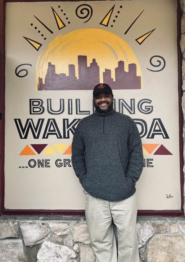 Image of Marcus Davis, owner of The Breakfast Klub, standing in front of a mural.