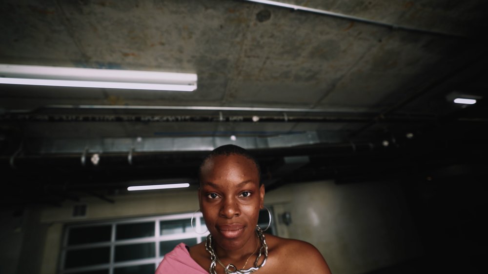 A woman, partly smiling, in an industrial-style room