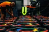 A line of race car wheels with the blue, green, yellow and red Chrome-inspired logo colors around them. A person in an orange shirt is doing maintenance on one of them.