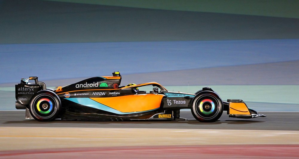 An orange, blue and black race car decorated with Android and Chrome logos on the engine and wheel covers.