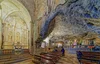 A natural cave formation with a rocky altar carved in, with steps and 2 rows of long benches.