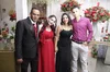 Micka, in a black dress, poses with three other family members. They are wearing formal clothing and have bouquets of flowers behind them.
