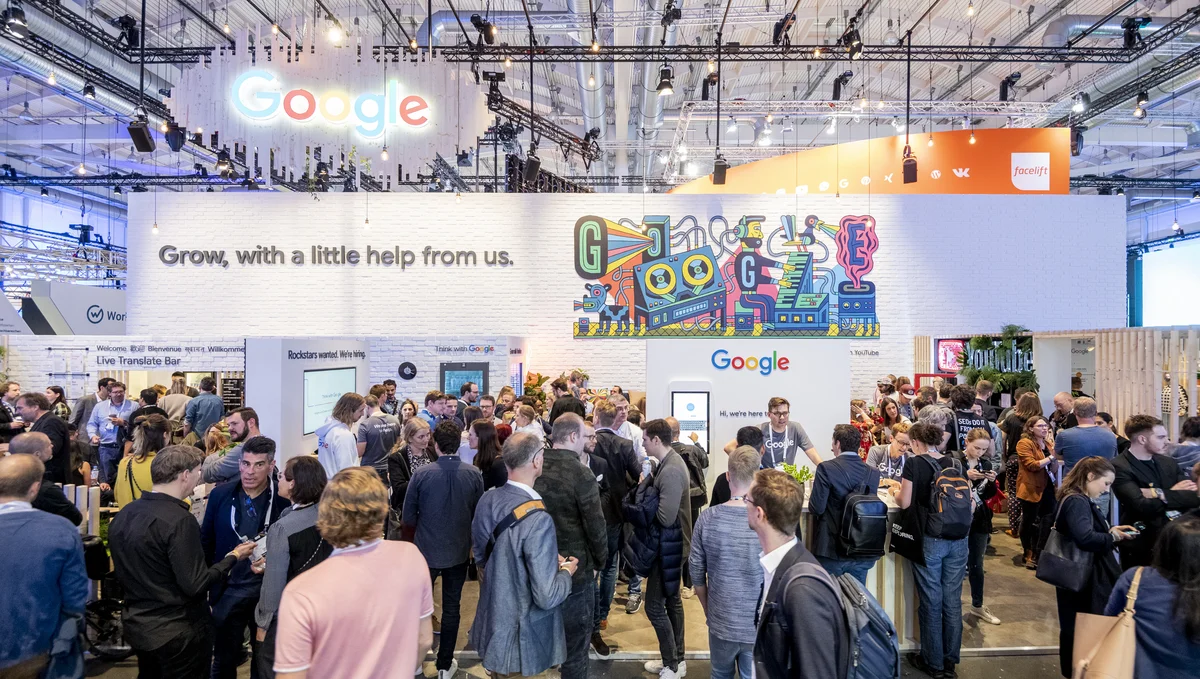 Besucherinnen und Besucher stehen vor dem Google-Stand auf der OMR 2019. Auf einer weißen Wand steht "Grow, with a little help from us."