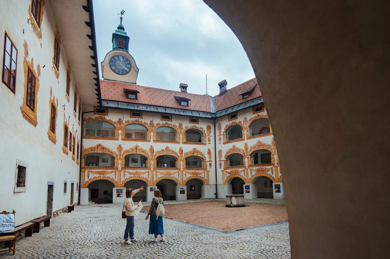 The courtyard of a castle with a clock tower in the middle of it and ornate gold-yellow window decorations