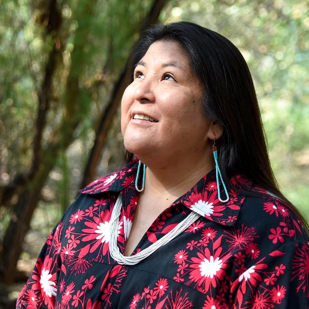 Portrait photo of Shayai Lucero, who wears a black and red shirt and turquoise earrings.