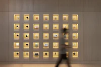 A person walks past a gallery of Nest products, each individually encased in a small lit-up box.