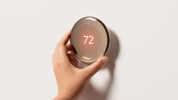 Hand adjusting the Nest Thermostat in Polished Gold