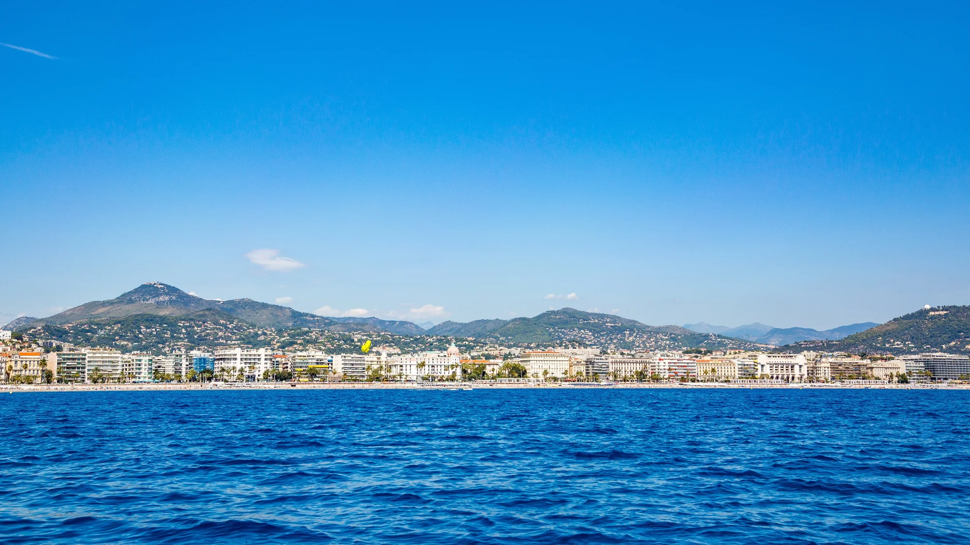 Blue sea reflecting the blue skies with the city of Nice on the coastline.