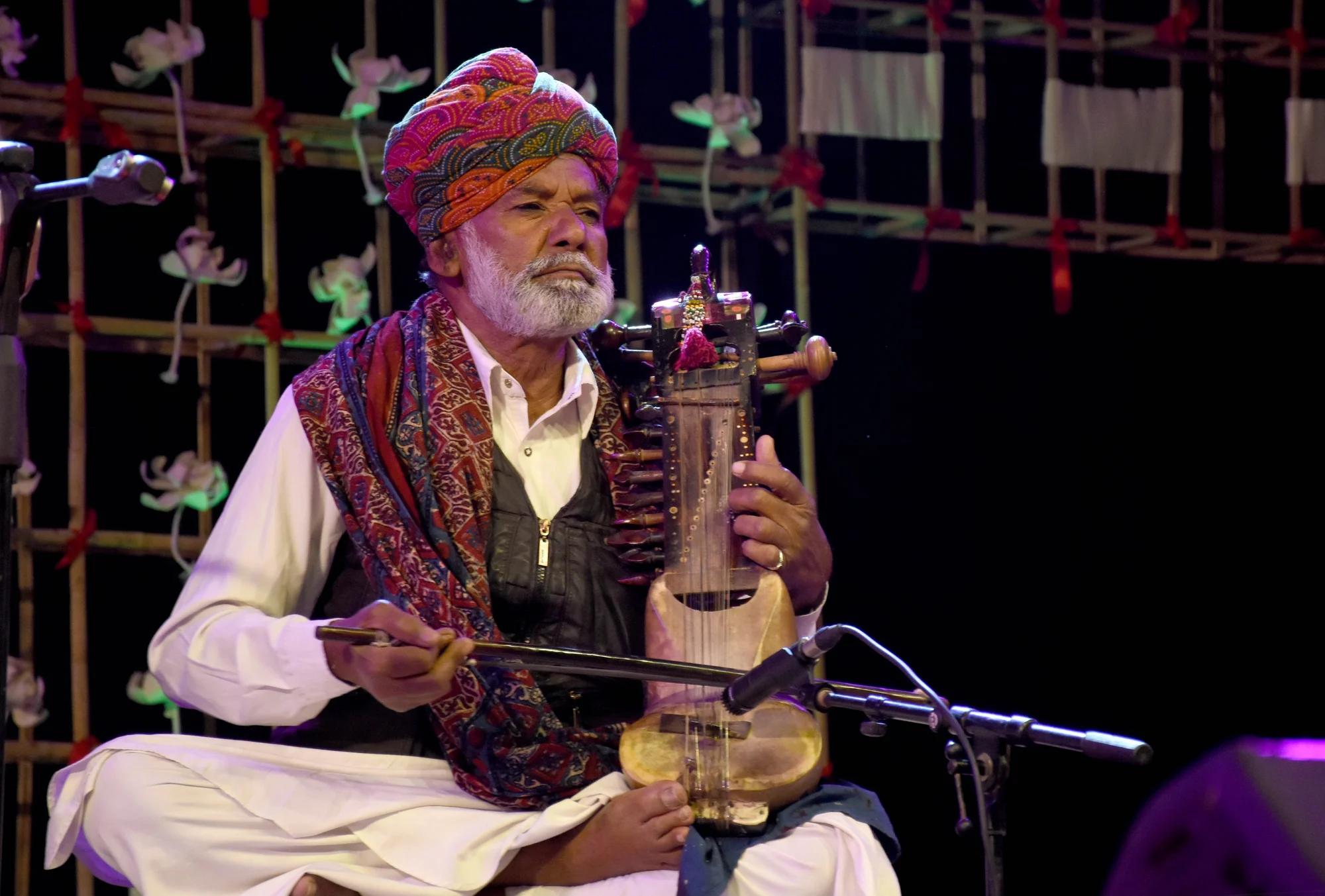 Noore Khan Langa on a stage playing a traditional instrument called Sindhi Sarangi