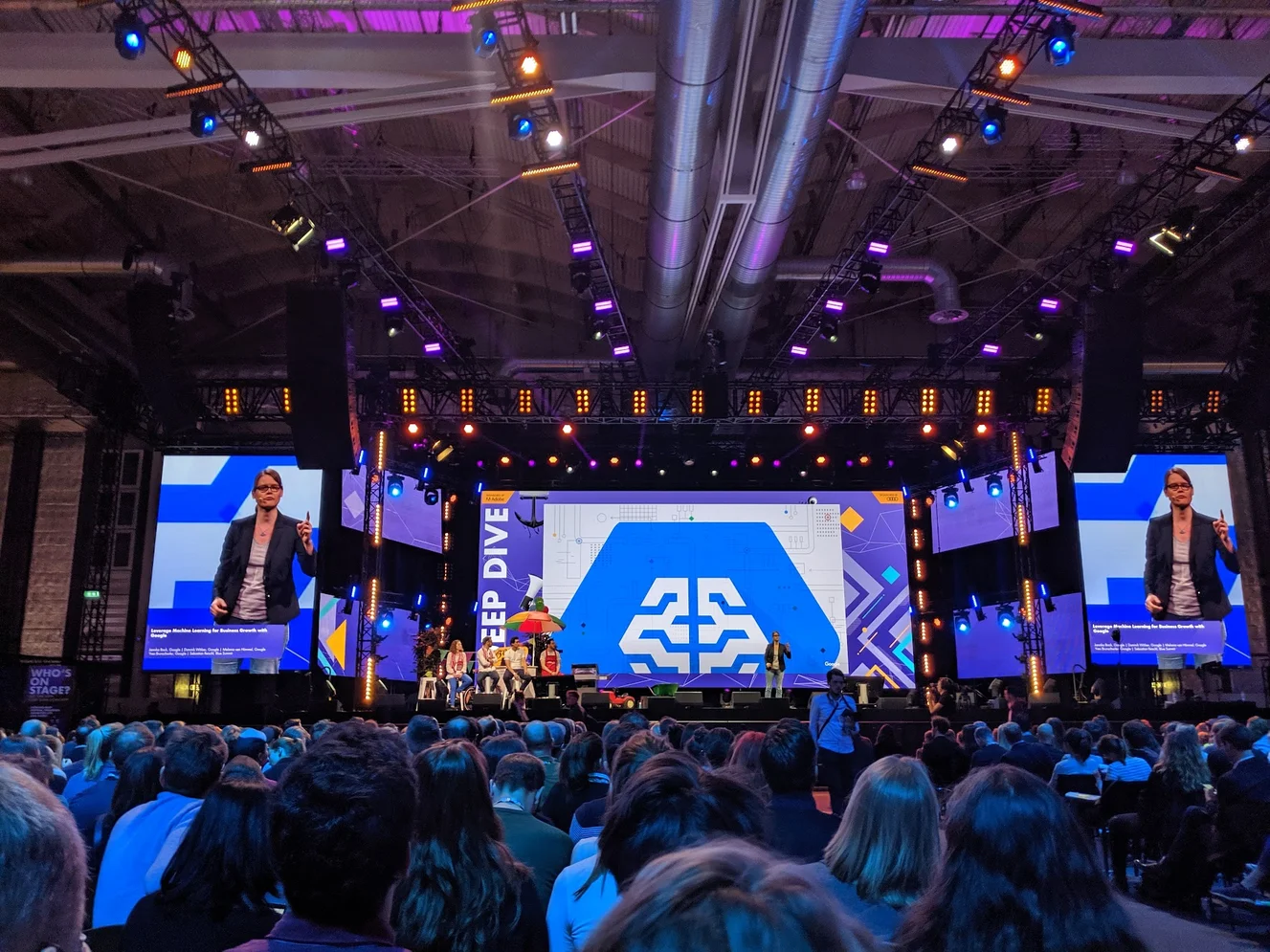 Jannika steht auf einer Bühne in den Messehallen Hamburgs beim OMR Festival. Vor ihr sitzen Hunderte Zuschauer:innen, neben und hinter ihr sind große Screens, auf denen sie ebenfalls zu sehen ist.