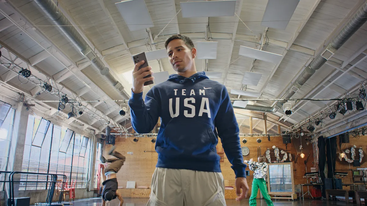 Victor Montalvo standing in a studio looking at his phone wearing blue sweatshirt that says Team USA