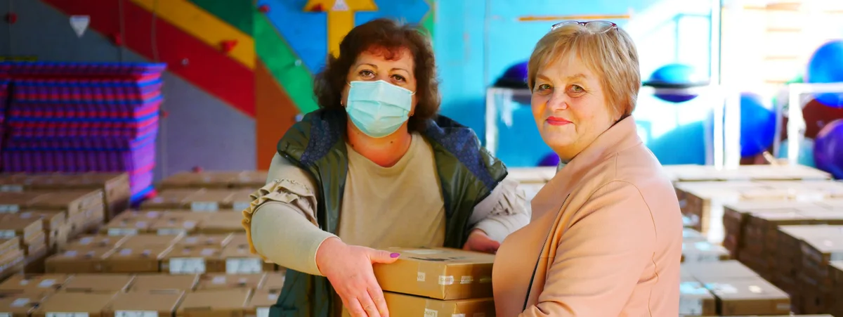 Image shows two women holding boxes of chrome books