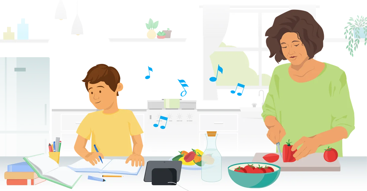 A mother cooks dinner in the kitchen as a child sits next to her doing their homework. The child is using Google Assistant on their Nest Hub Max, which is playing music.