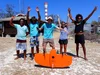 A group of five people posing with their arms up behind the drone they use to survey dugongs