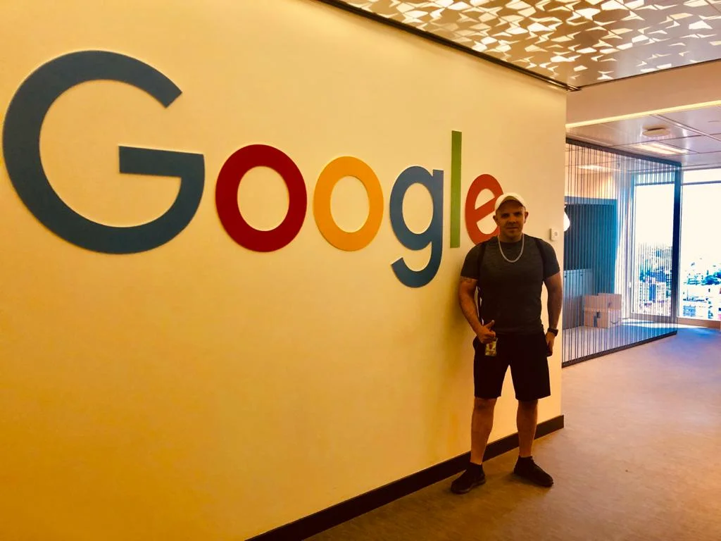 Leandro de p[e em frente a uma parede do escritório do Google em São Paulo.