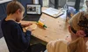 Two children roll out dough while watching an instructional video on YouTube