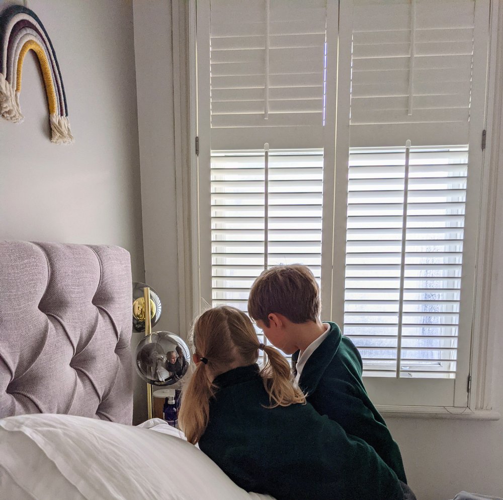 photo of two children in a bedroom crowding around and looking intently at a nightstand