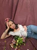 YouTube Creator Aliyah Simone poses in jeans and a white ruffled shirt with flowers in her hair