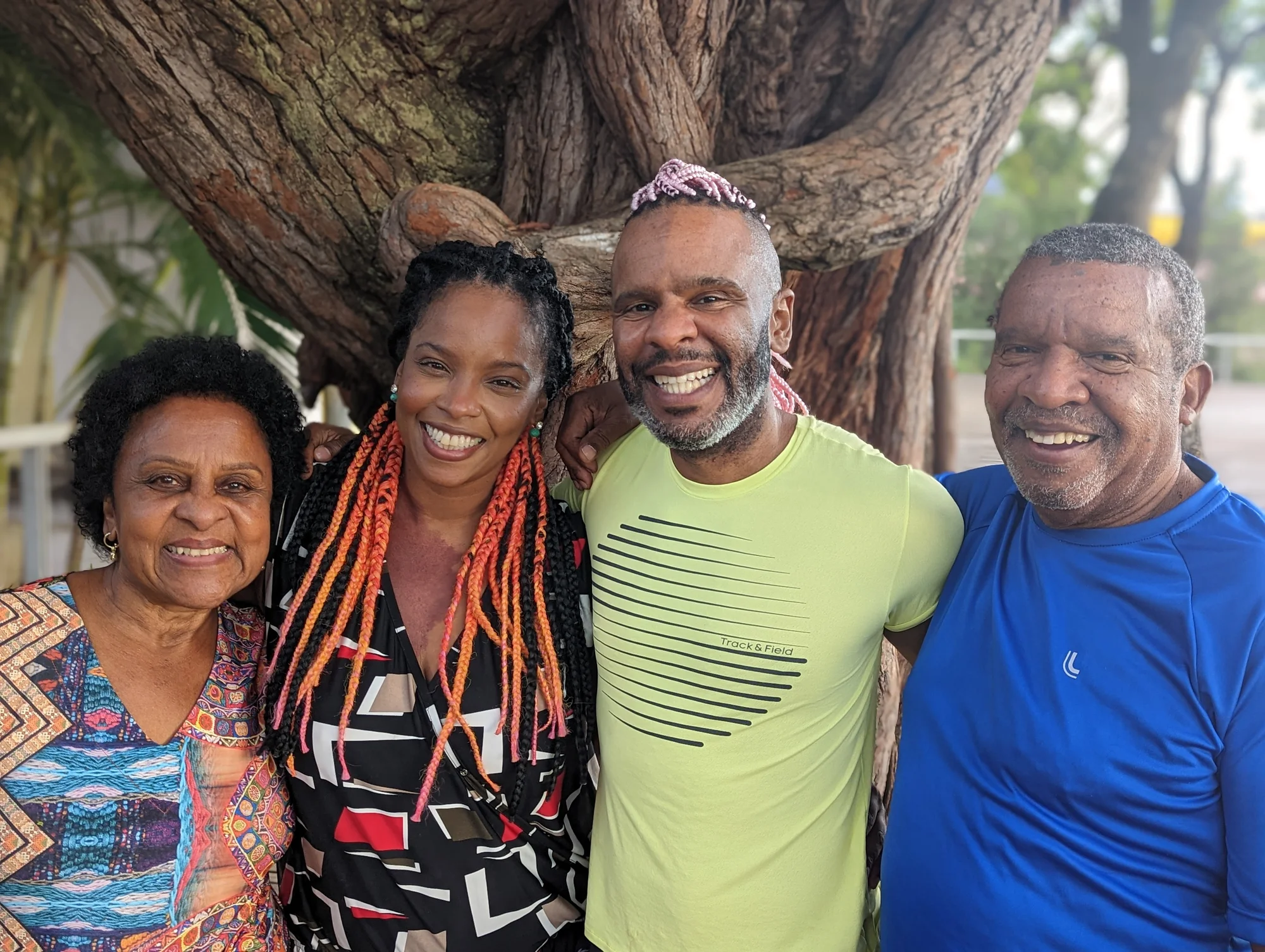 Daniel Castro do Nascimento mit seinen Eltern und seiner Schwester in Belo Horizonte in Brasilien. Sie stehen vor einem alten Baum und lächeln in die Kamera.