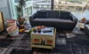 A space in a Google office with a couch, a table and chairs for kids with a chalkboard top that's covered in books and toys, two baskets filled with toys, and various toys and children's books scattered across two side tables and the floor.