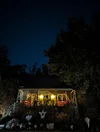A photo of a house with various Halloween decorations and the night sky lit up with stars above it.